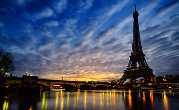 France: shot of the illuminated Eiffel Tower at dusk, the lights reflected on water in the foreground