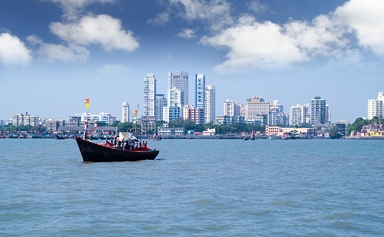 India: Skyline of Mumbai, in the foreground a moving colourful ship