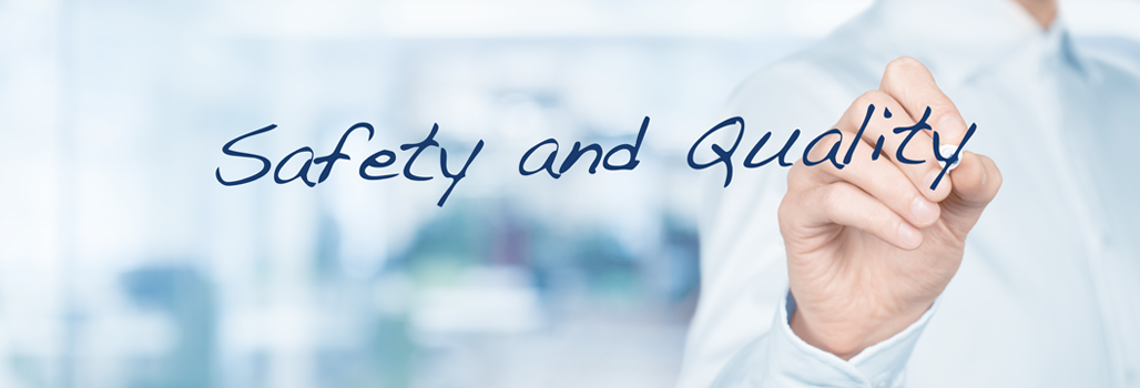 A man writes "Safety and Quality" on a glass board