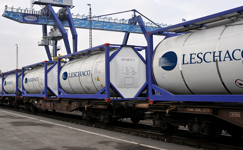 Tank container: Many tank containers on a freight train. The white tank containers are printed with a large Leschaco logo