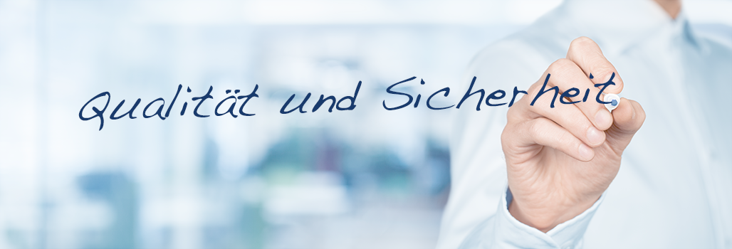 Ein Mann schreibt „Safety and Quality“ auf eine Glaswand Ein Mann schreibt „Safety and Quality“ auf eine Glaswand