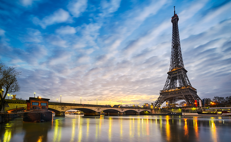 France: shot of the illuminated Eiffel Tower at dusk, the lights reflected on water in the foreground